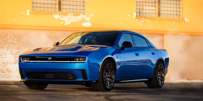 A Dodge Charger parked with its front facing slightly left, against a yellow wall.