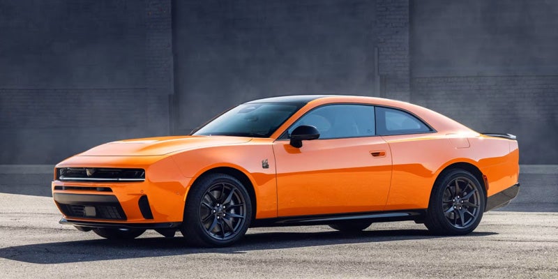 Sleek orange sports car with a black roof, black wheels, and a small black spoiler.
