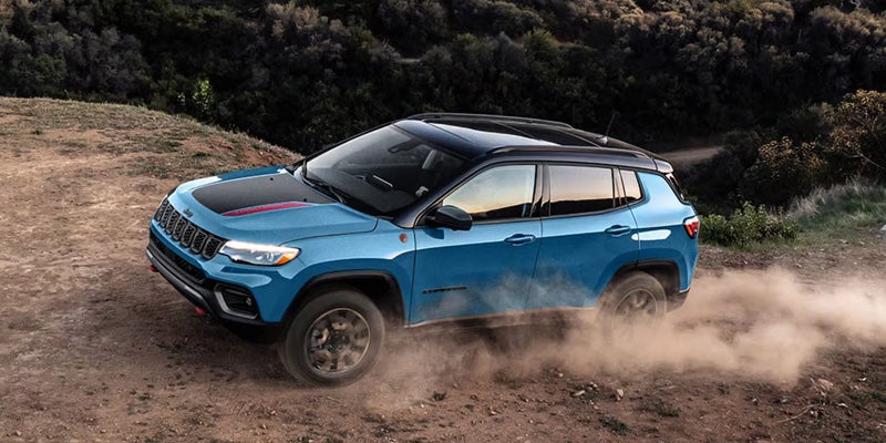 Blue 2026 Jeep Compass driving through dusty roads
